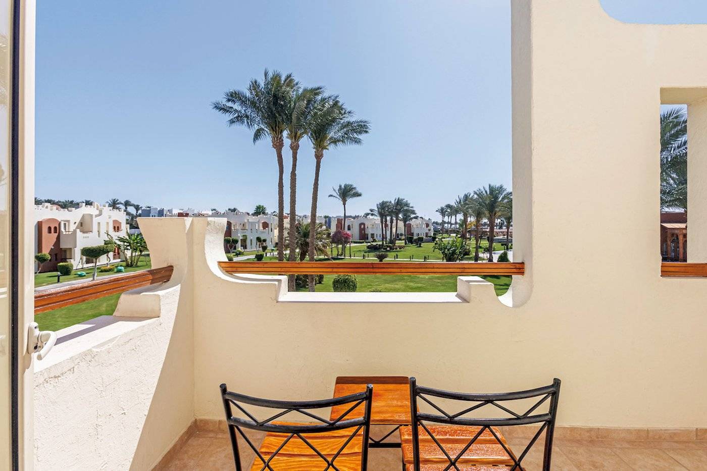 Ein Balkon des SUNRISE Royal Makadi Resort mit Blick auf Palmen und einen Garten.