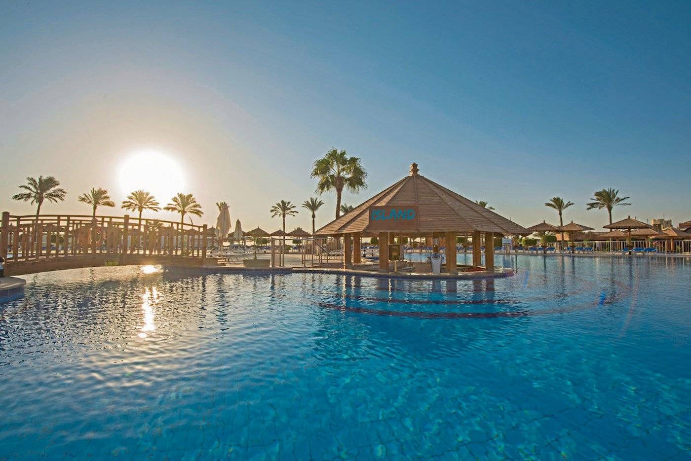 Außenpool im Sunrise Royal Makadi Resort mit Sonnenuntergang im Hintergrund.