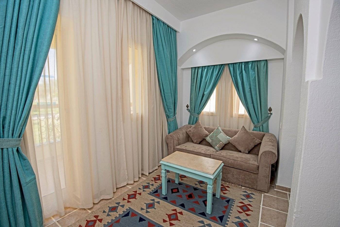 Wohnzimmer mit Sofa, Tisch, blauen Vorhängen und Teppich.
