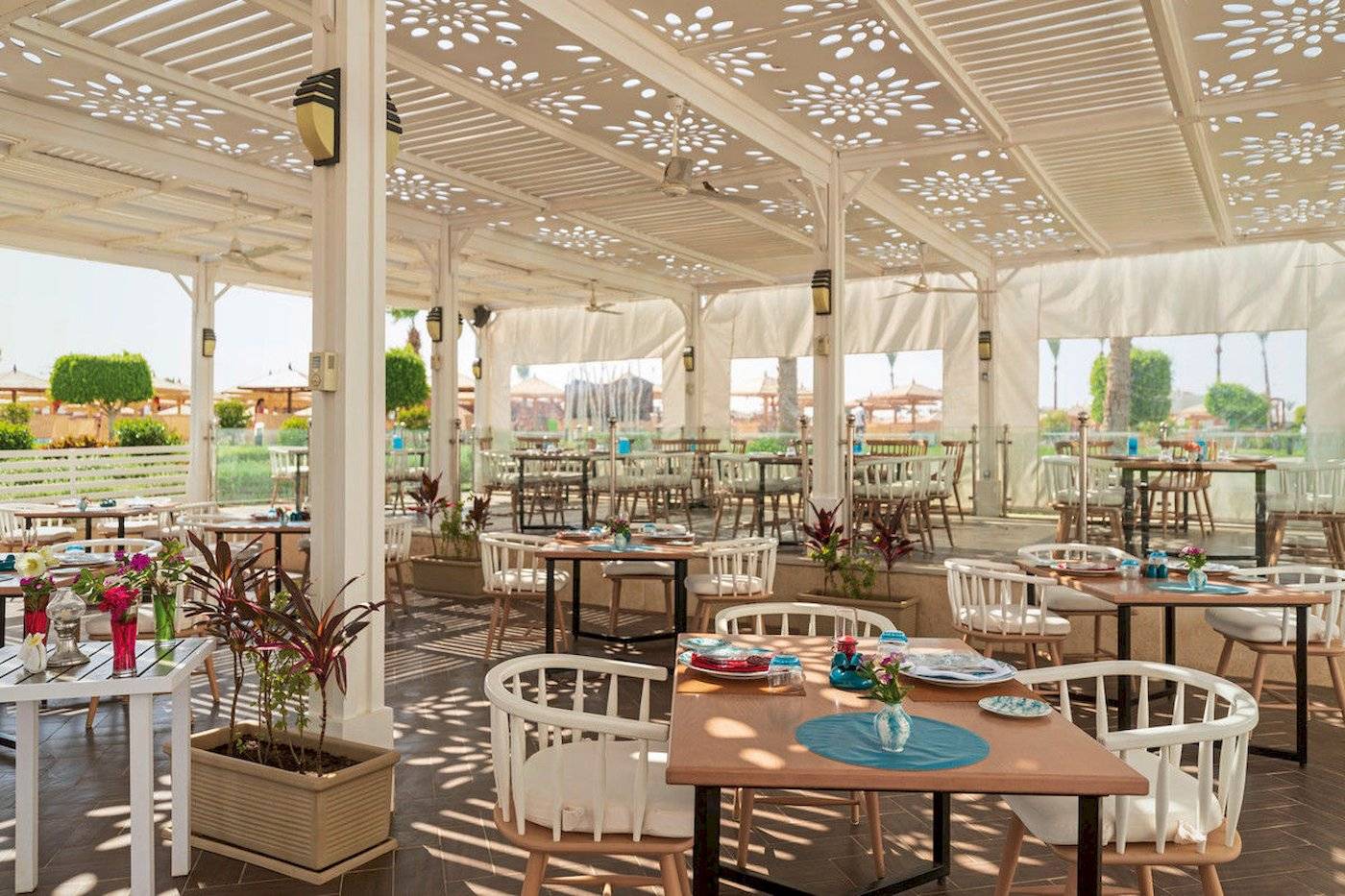 Restaurantbereich des Sunrise Royal Makadi Resorts mit beschatteten Tischen und Stühlen