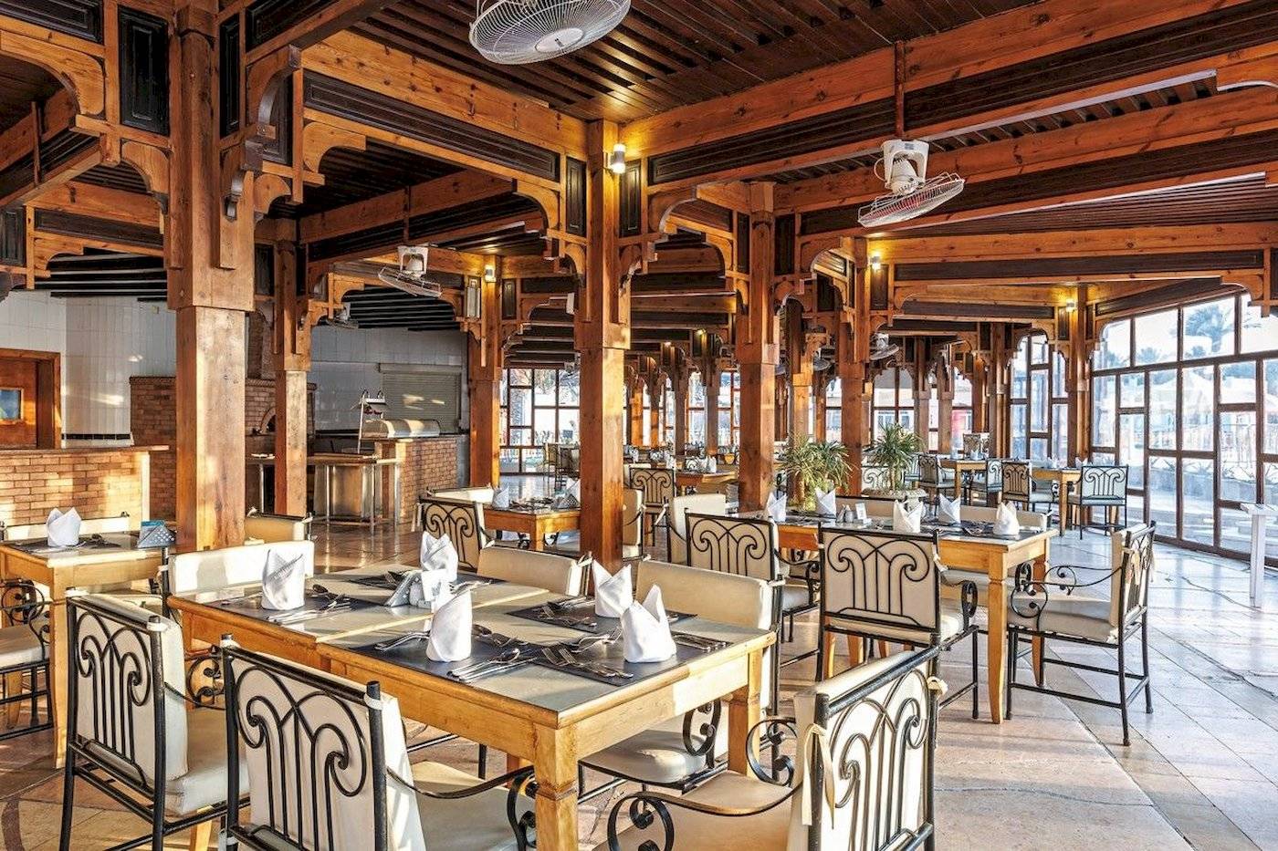 Restaurant des Sunrise Royal Makadi Resort mit Holzmöbeln und Deckenventilatoren.