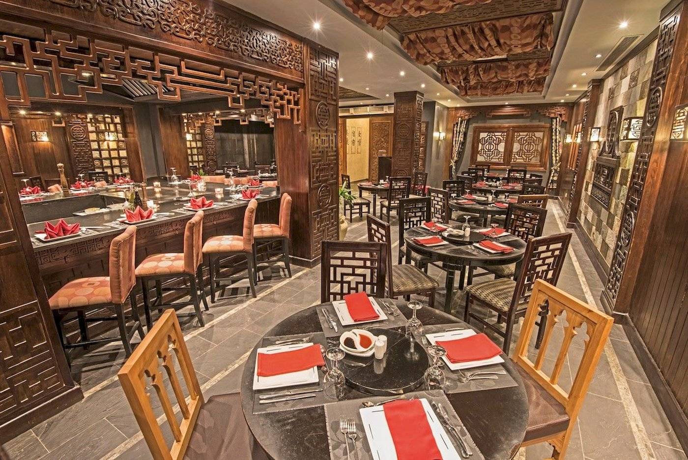 Innenansicht des Restaurants im Sunrise Royal Makadi Resort mit runden Tischen, Stühlen und Holzdesign.