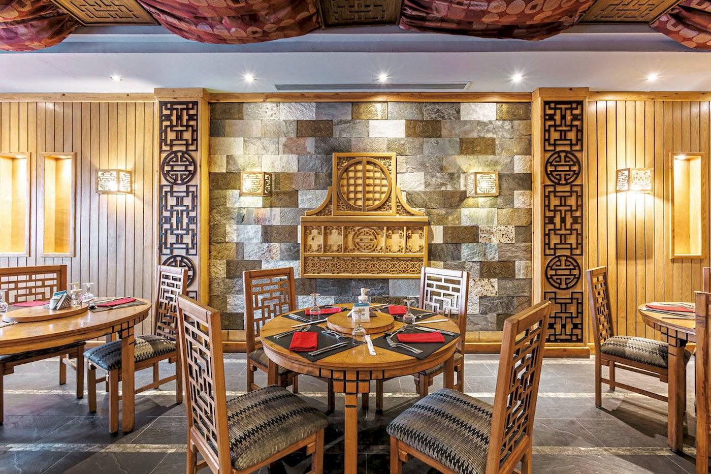 Innenbereich des Sunrise Royal Makadi Resort mit runden Tischen und Holzwänden.