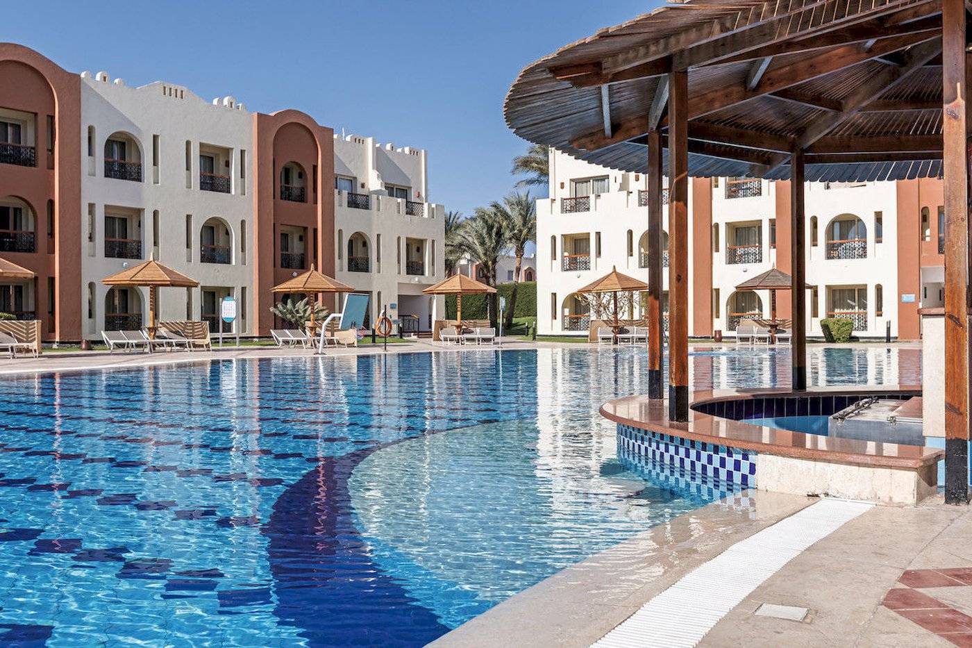 Pool-Bereich des Sunrise Royal Makadi Resorts mit umliegenden Gebäuden und Sonnenschirmen.