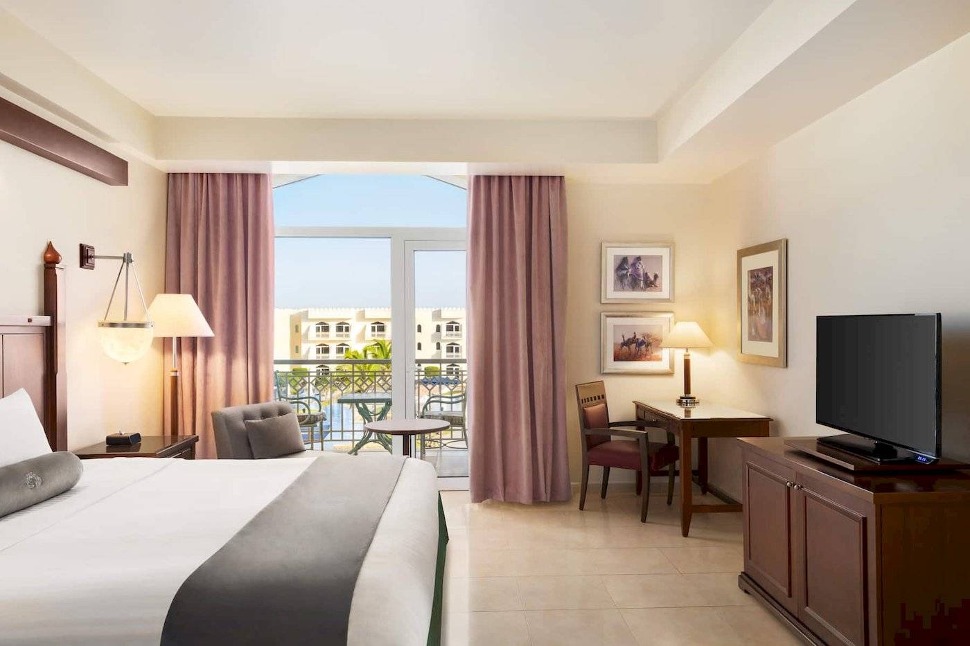 Hotelzimmer im Wyndham Garden Salalah Mirbat mit Balkon, Fernseher und Schreibtisch.