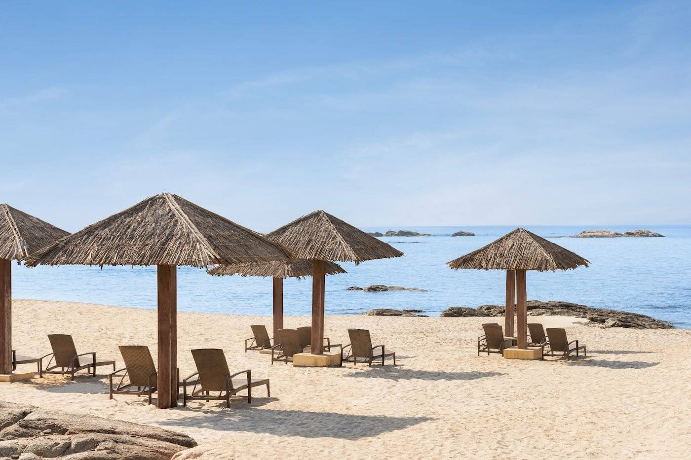 Strand des Wyndham Garden Salalah Mirbat mit Liegen unter Strohdächern