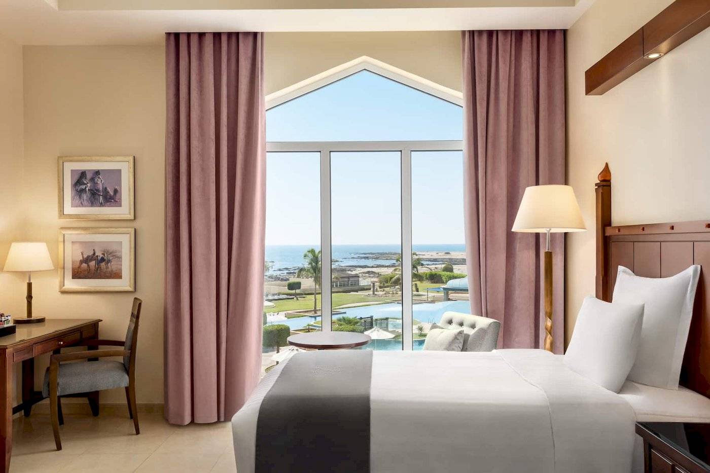Zimmer im Wyndham Garden Salalah Mirbat Hotel mit Meerblick, großes Bett, Schreibtisch und Panoramafenster.