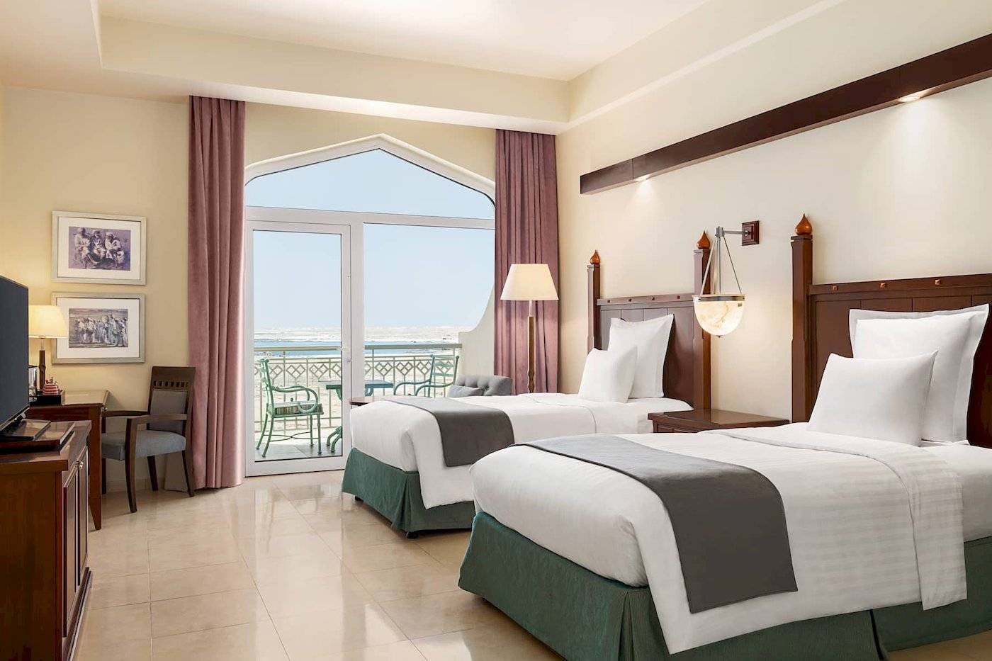 Hotelzimmer mit zwei Betten, Blick auf das Meer und einen Balkon.