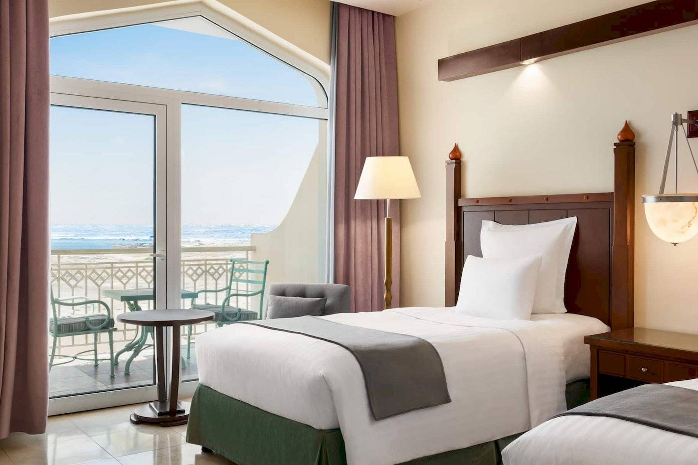 Zimmer im Wyndham Garden Salalah Mirbat Hotel mit Blick auf das Meer von einem Balkon.