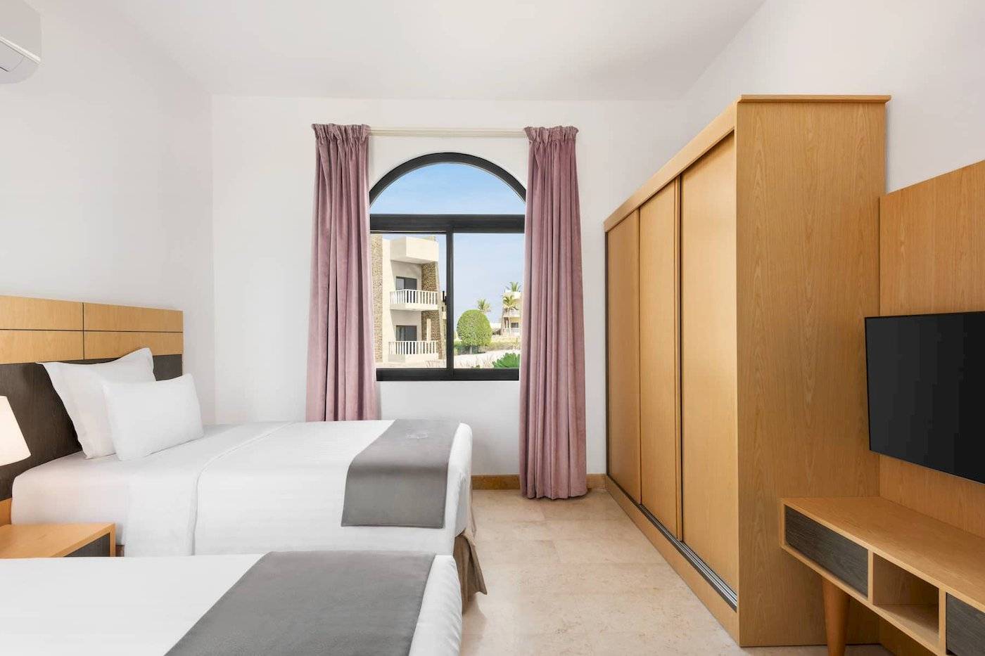 Hotelzimmer im Wyndham Garden Salalah Mirbat mit zwei Betten und Aussichtsfenster.