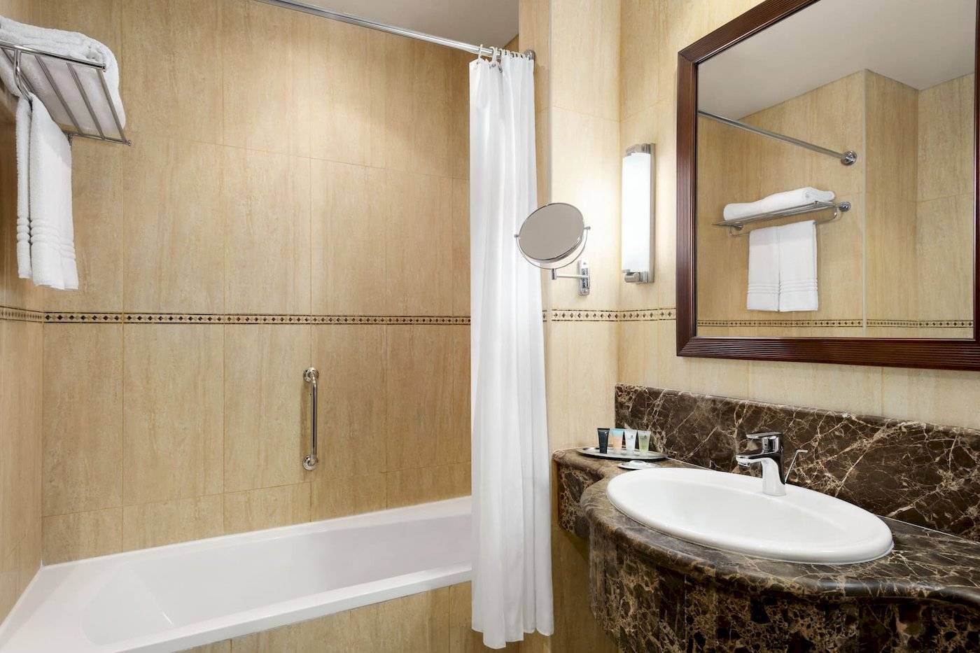 Badezimmer im Wyndham Garden Salalah Mirbat Hotel mit Badewanne, Waschbecken und Spiegel.
