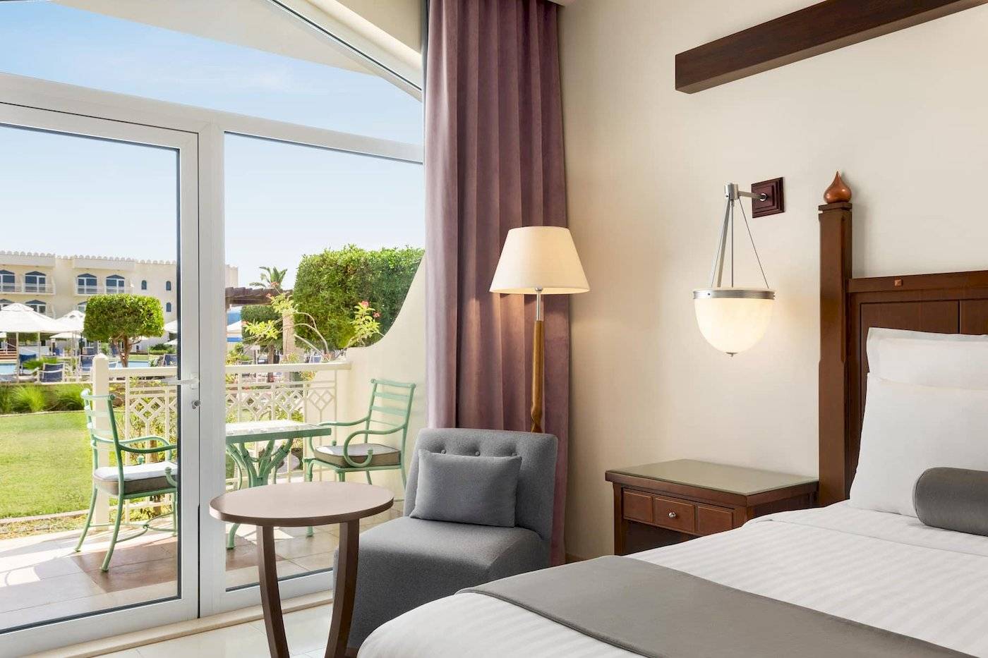 Zimmer im Wyndham Garden Salalah Mirbat Hotel mit Blick auf eine Terrasse und Garten.
