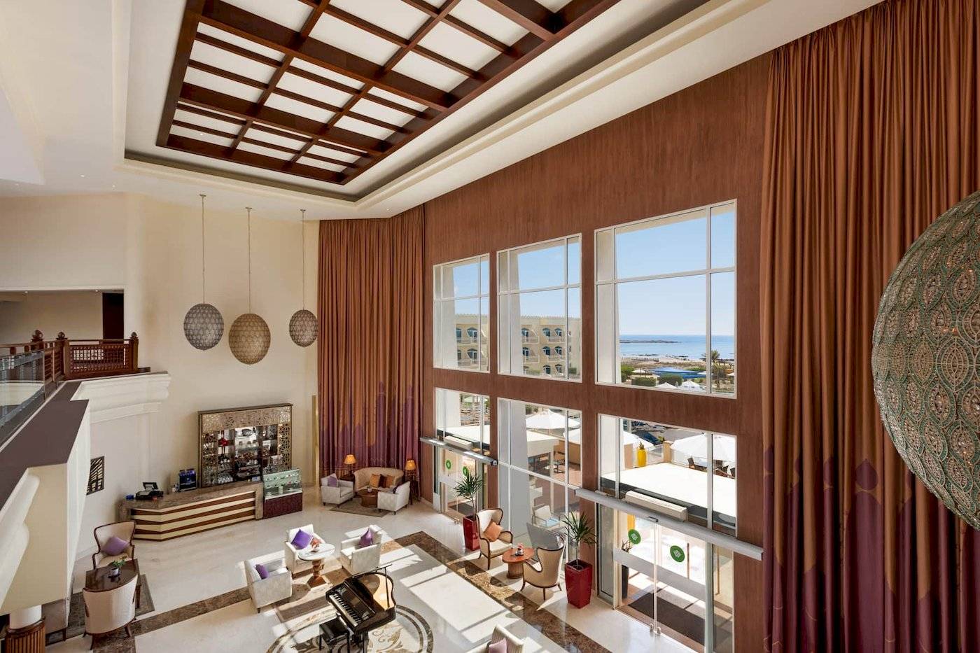 Einblick in die Lobby des Wyndham Garden Salalah Mirbat Hotels mit Innendekoration, Fenstern und Meerblick.