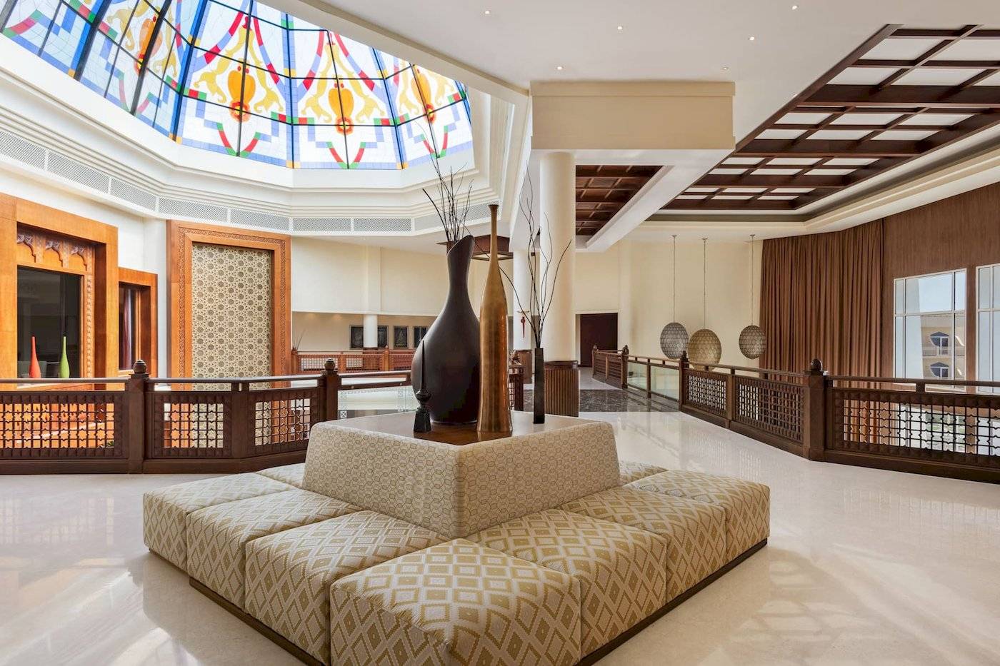 Empfangshalle des Wyndham Garden Salalah Mirbat mit Sitzecke, Vasen und buntem Glasdach