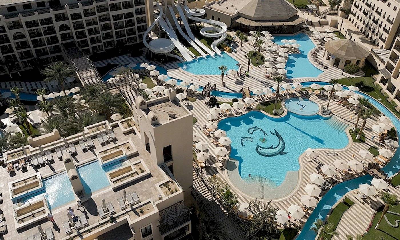 Luftaufnahme des Steigenberger Aqua Magic Hotels mit mehreren Schwimmbecken, Wasserrutschen und Sonnenschirmen.