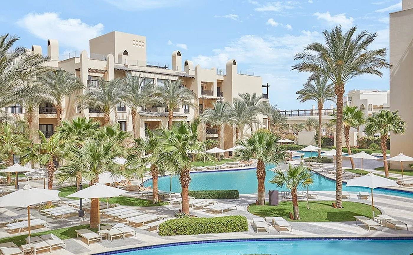 Außenbereich des Steigenberger Aqua Magic Resorts mit Pool, Palmen und Liegestühlen.
