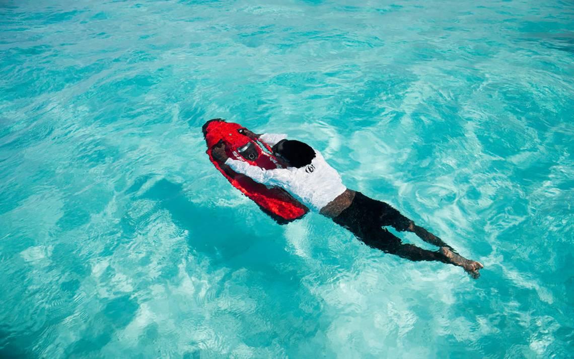 Person schwimmt im blauen Wasser mit roter Ausrüstung