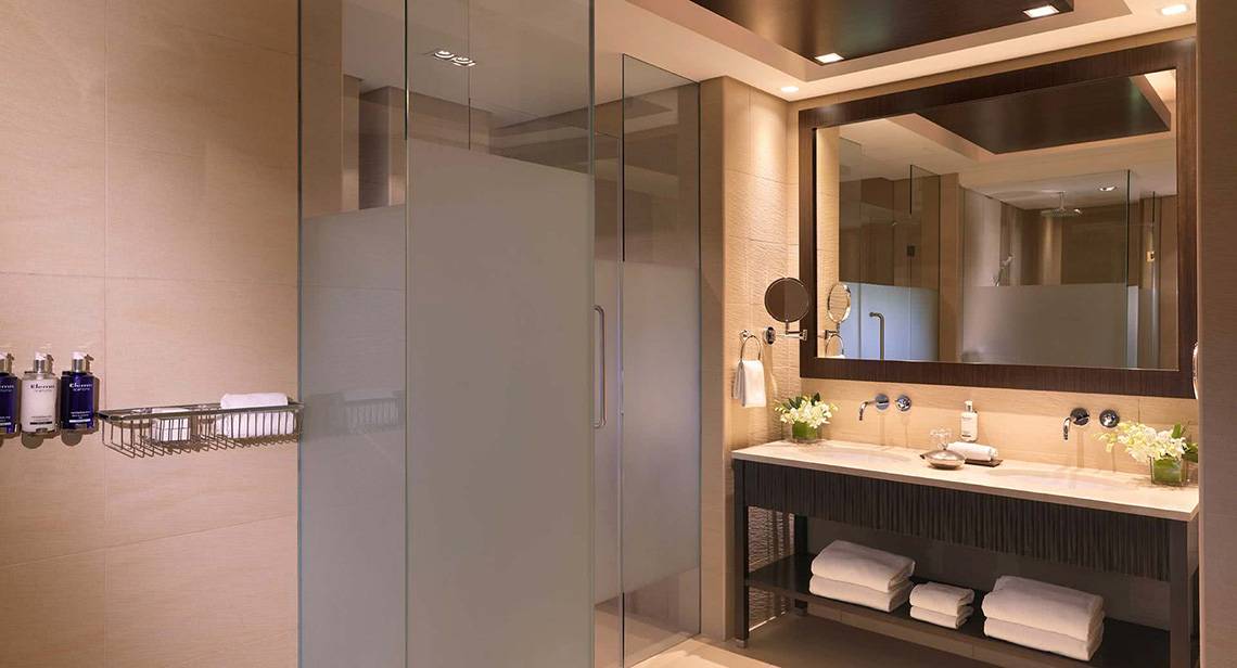 Badezimmer im Anantara The Palm Dubai Resort mit Glasdusche, Waschbecken und Spiegel.