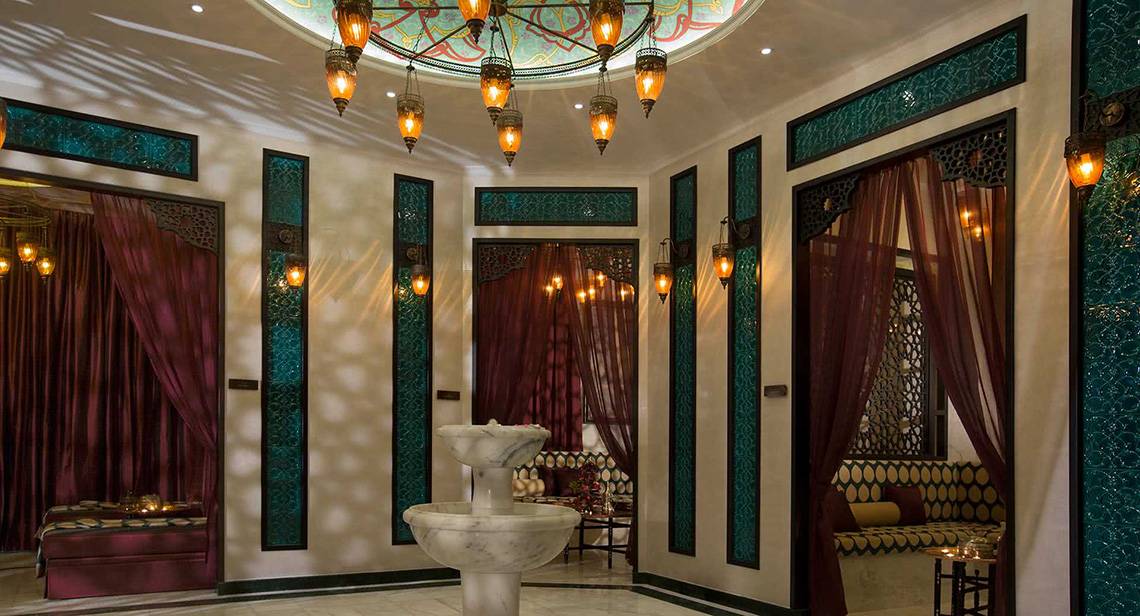 Innenbereich des Anantara The Palm Dubai Resorts mit Brunnen, roten Vorhängen und türkisfarbenen Akzenten.