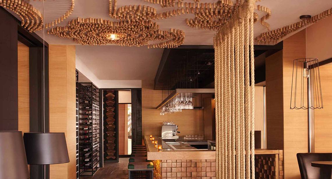 Innenansicht der Bar im Anantara The Palm Dubai Resort mit Holzelementen, einer Theke und einer Deckengestaltung aus Korken.