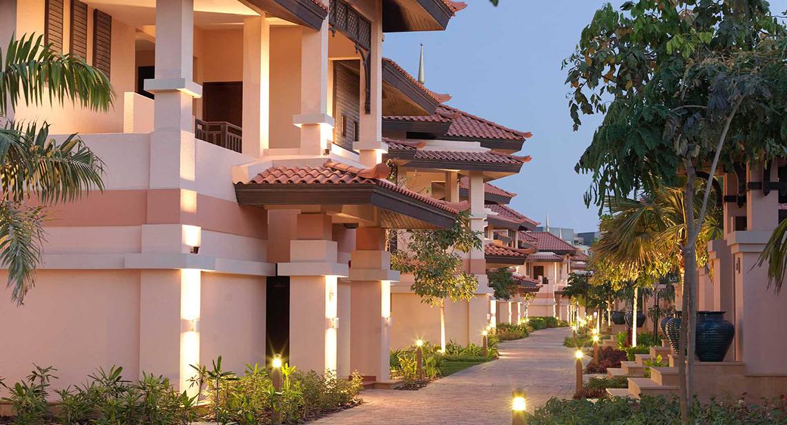 Abendansicht der Anantara The Palm Dubai Resort Villas mit illuminierten Wegen und gut beleuchteten Gebäuden.