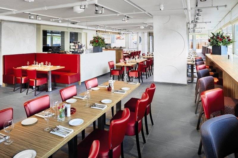 Innenansicht des Casa Amsterdam Restaurants mit roten Stühlen und Tischen.