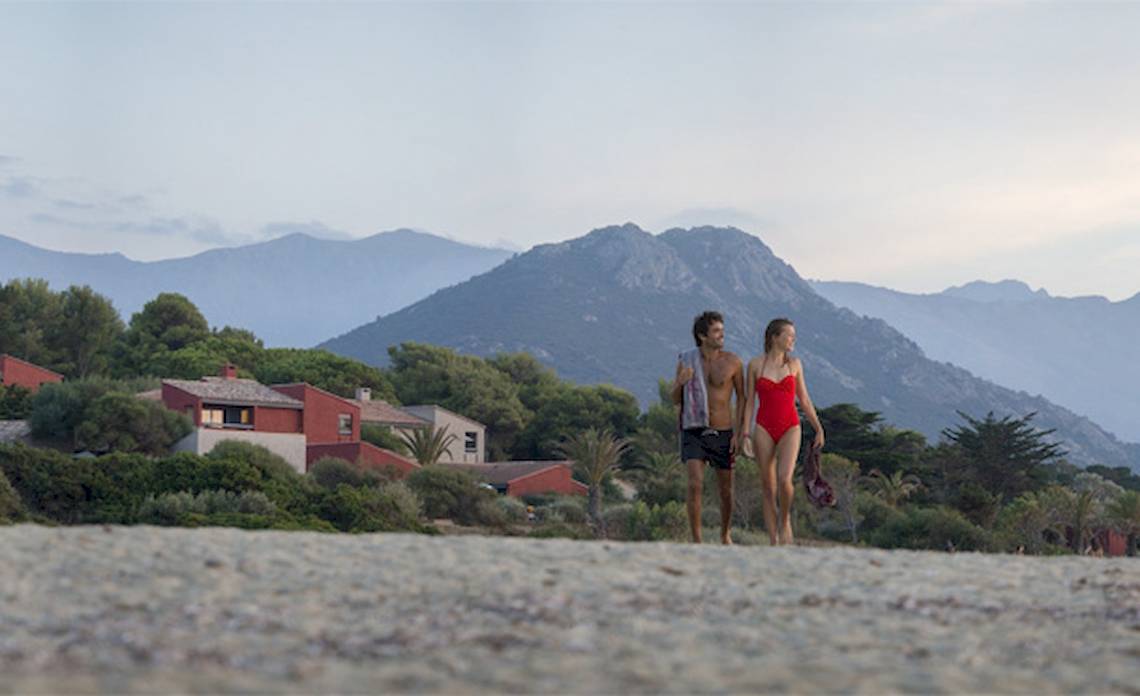 Paar am Strand vor dem Hotel Belambra Club Golfe de Lozari mit Blick auf die Berge