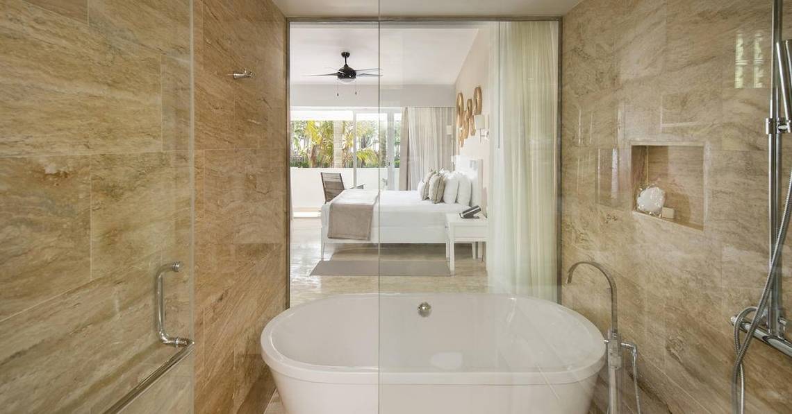 Badezimmer im Melia Caribe Beach Resort mit Badewanne, Dusche und Blick auf das Schlafzimmer.