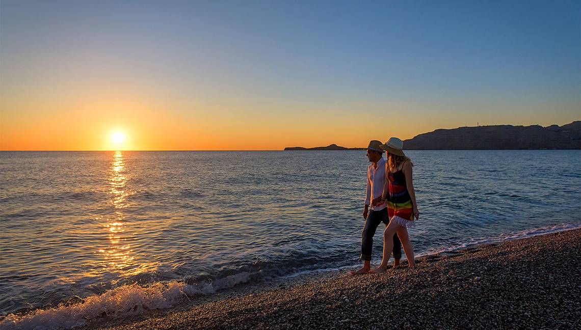 Paar genießt Sonnenuntergang am Strand des Atrium Palace Thalasso Spa Resort & Villas.