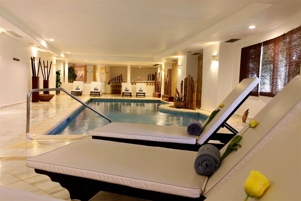 Innenpool des Bahia Principe Grand Jamaica mit Lounge-Liegestühlen und Blumendekoration.