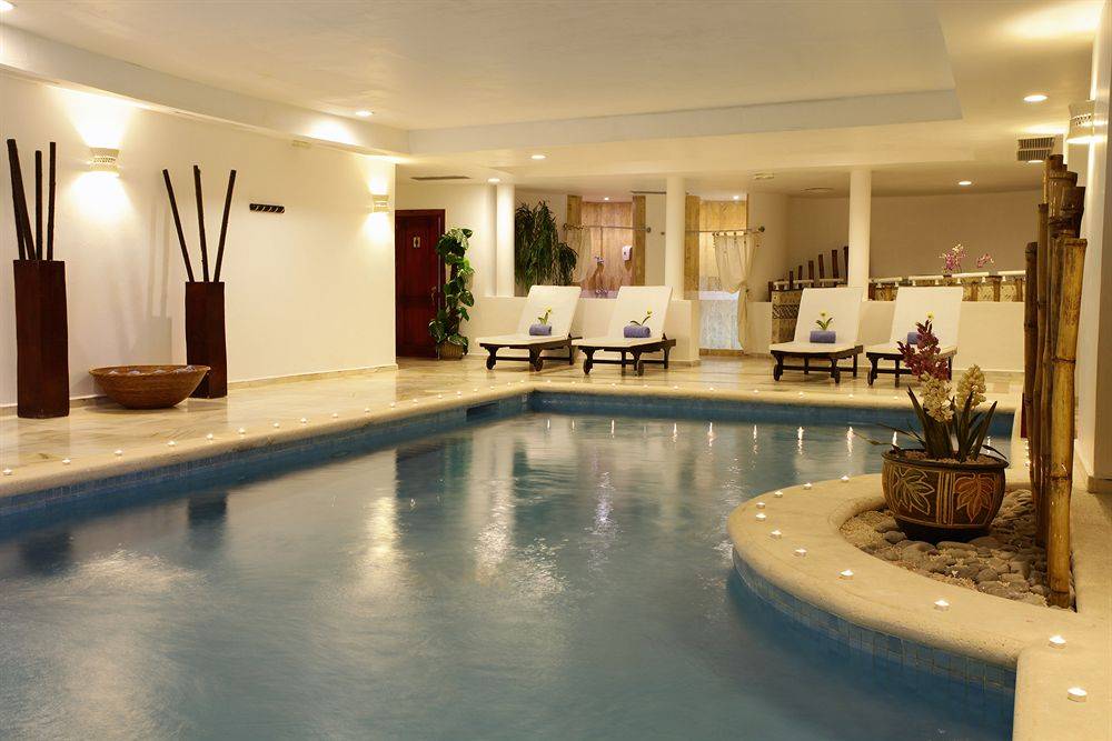 Pool-Loungebereich im Bahia Principe Grand Jamaica mit Loungestühlen und Pflanzen.