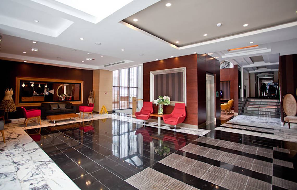 Lobby des Cettia Beach Resorts mit schwarzen und weißen Fliesen und roten Stühlen.