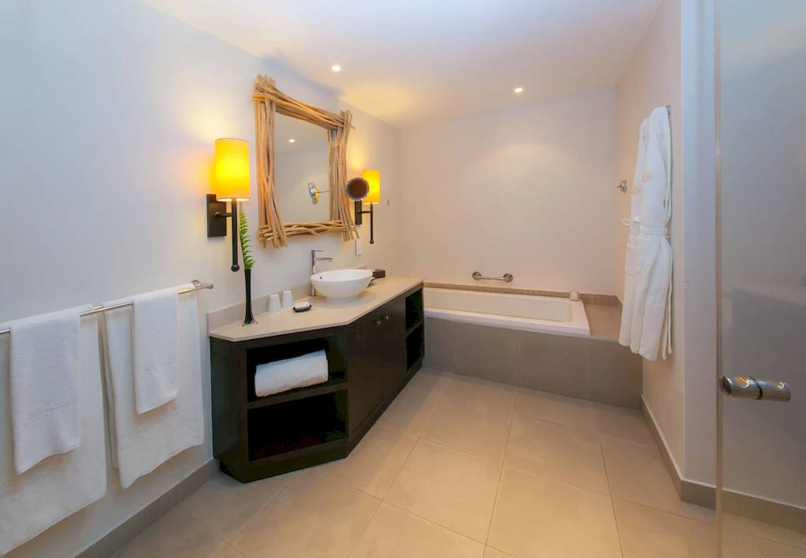 Ein modernes Badezimmer mit Badewanne, Waschbecken und großen Spiegel im Kempinski Seychelles Resort.