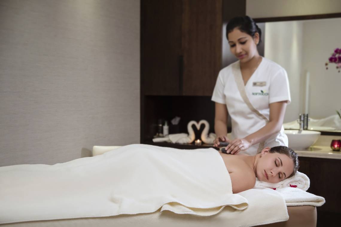 Eine Frau erhält eine Massage in einem Hotel-Spa, von einer Masseurin in weißer Uniform.