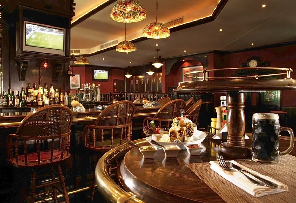 Innenansicht der Bar im Jumeira Rotana Hotel mit Sitzgelegenheiten und Getränken.