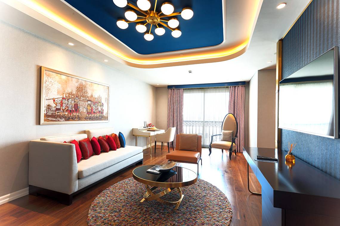 Wohnzimmer im Land of Legends Kingdom Hotel mit einem Sofa, einem Tisch und einem Fernseher.