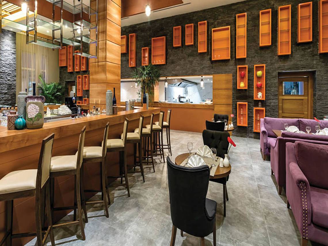 Restaurant im Land der Legenden Kingdom Hotel mit Bar, Stühlen und Tischen.