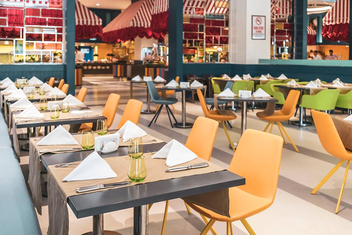 Restauranttische im Land of Legends Kingdom Hotel, alle mit Servietten und Besteck gedeckt.