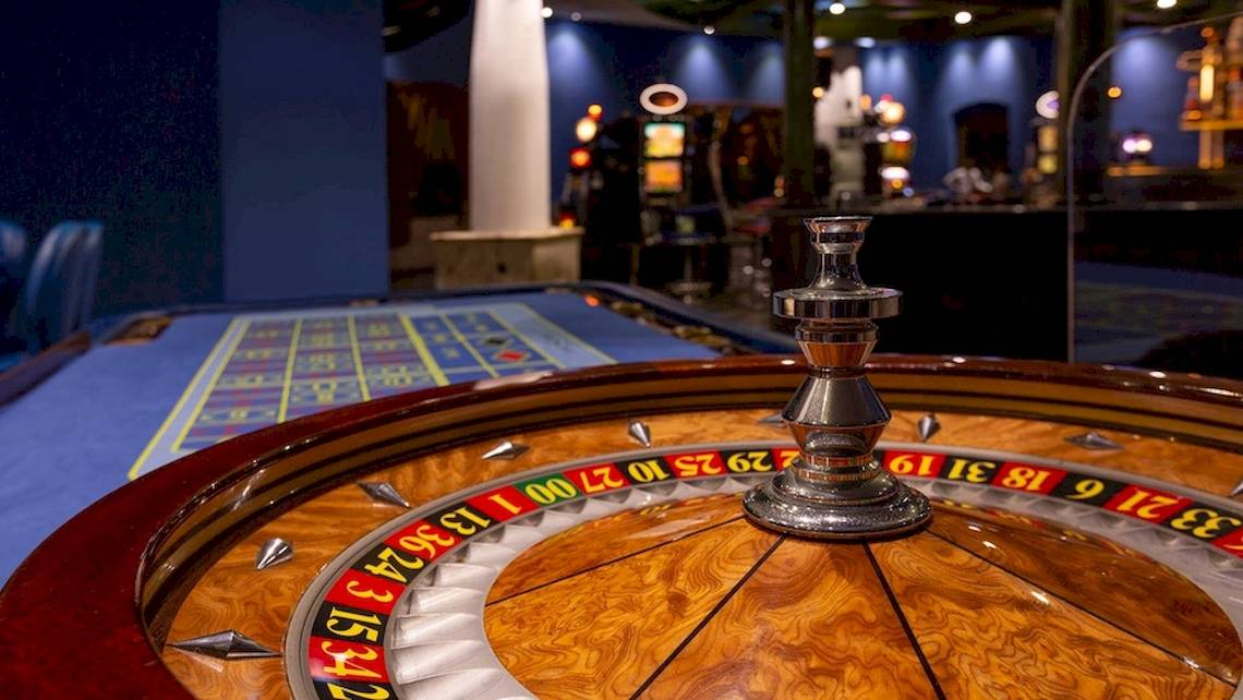 Casino-Spieltisch mit einem großen, auffälligen Roulette-Rad im Vordergrund.