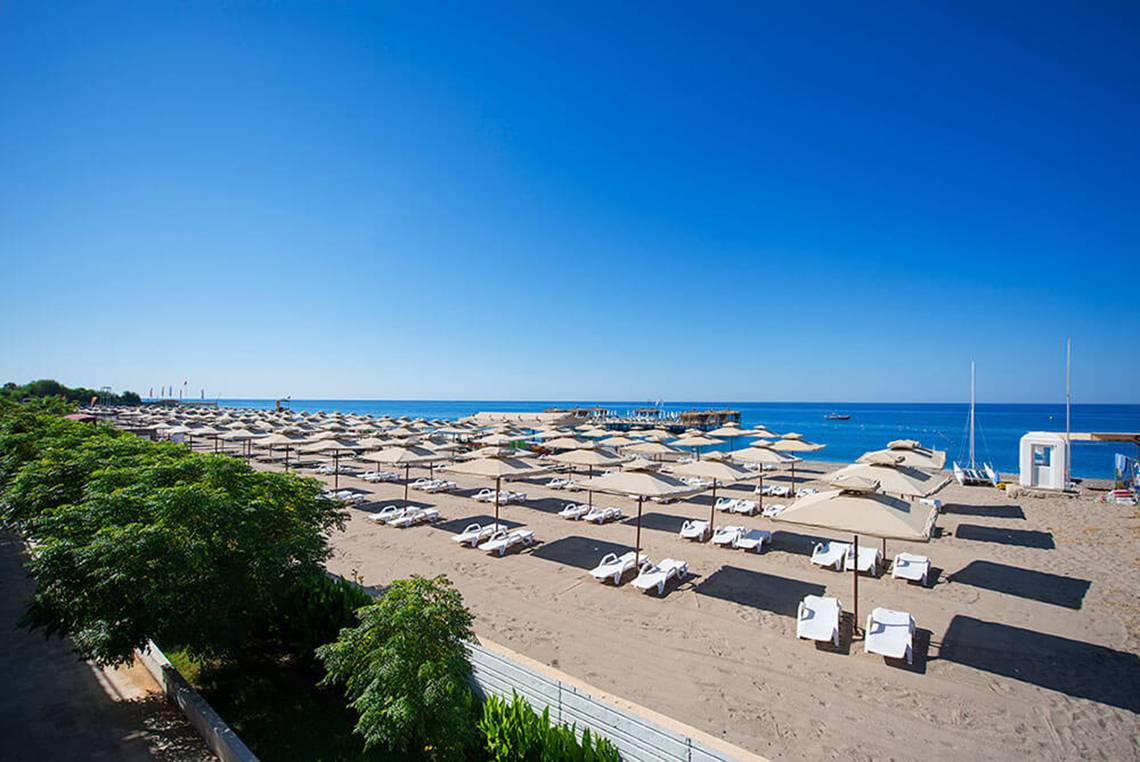 Strand des Club Nena mit vielen Sonnenliegen und Sonnenschirmen am Meer