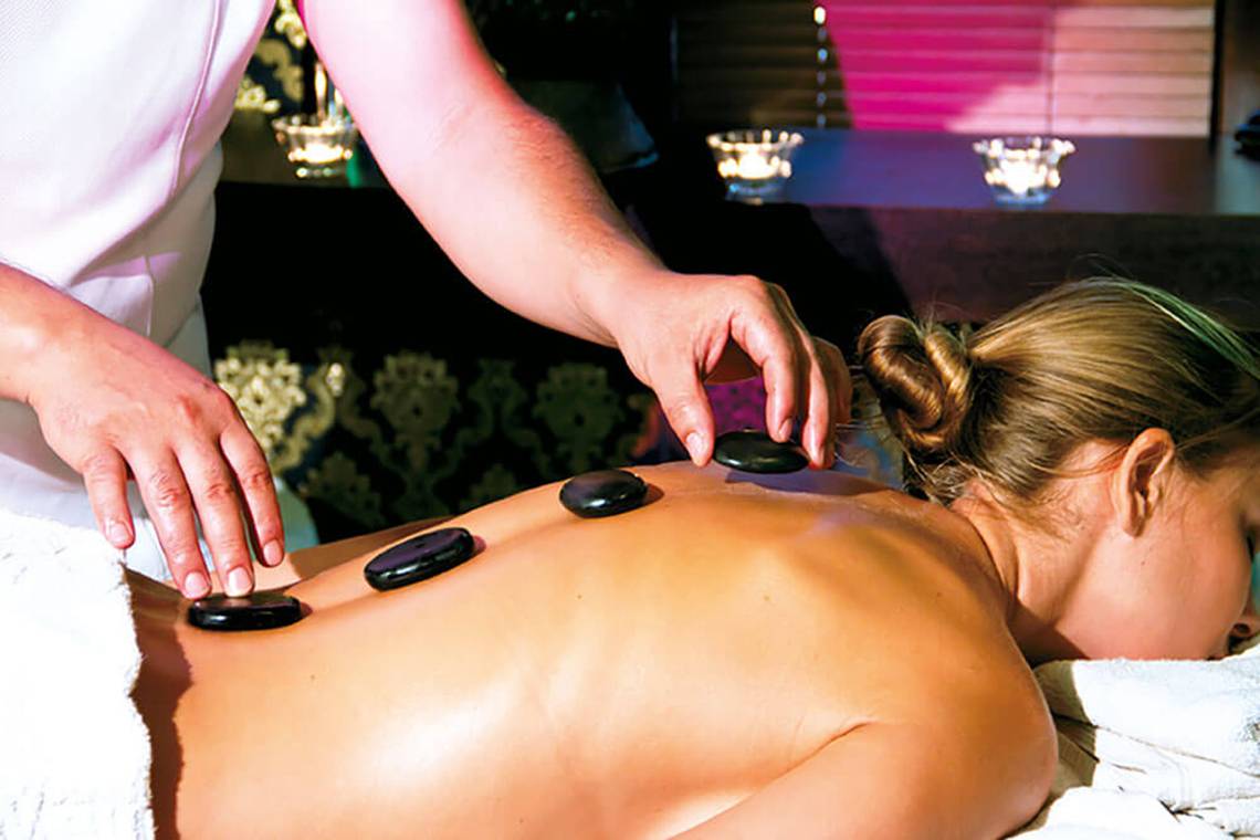 Eine Frau im Hotel Club Nena genießt eine Massage mit Steinen.