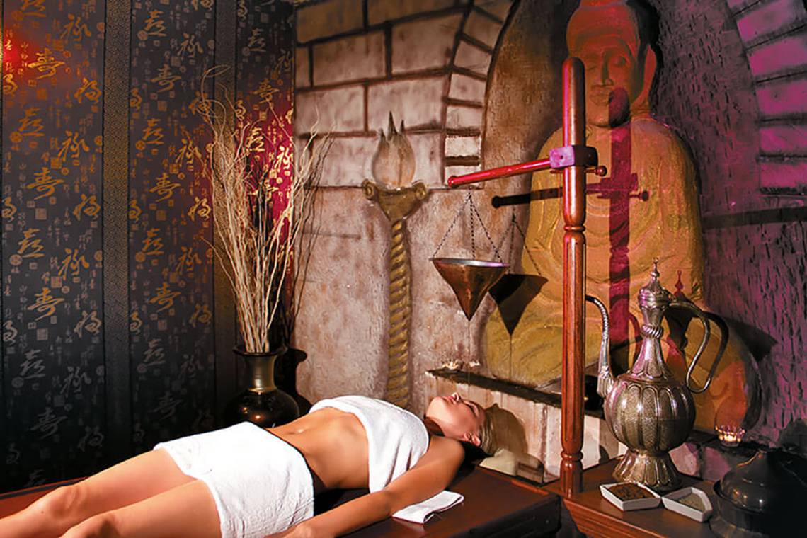Frau im Asiatischen Spa Salon mit orientalischen Dekor und Statue