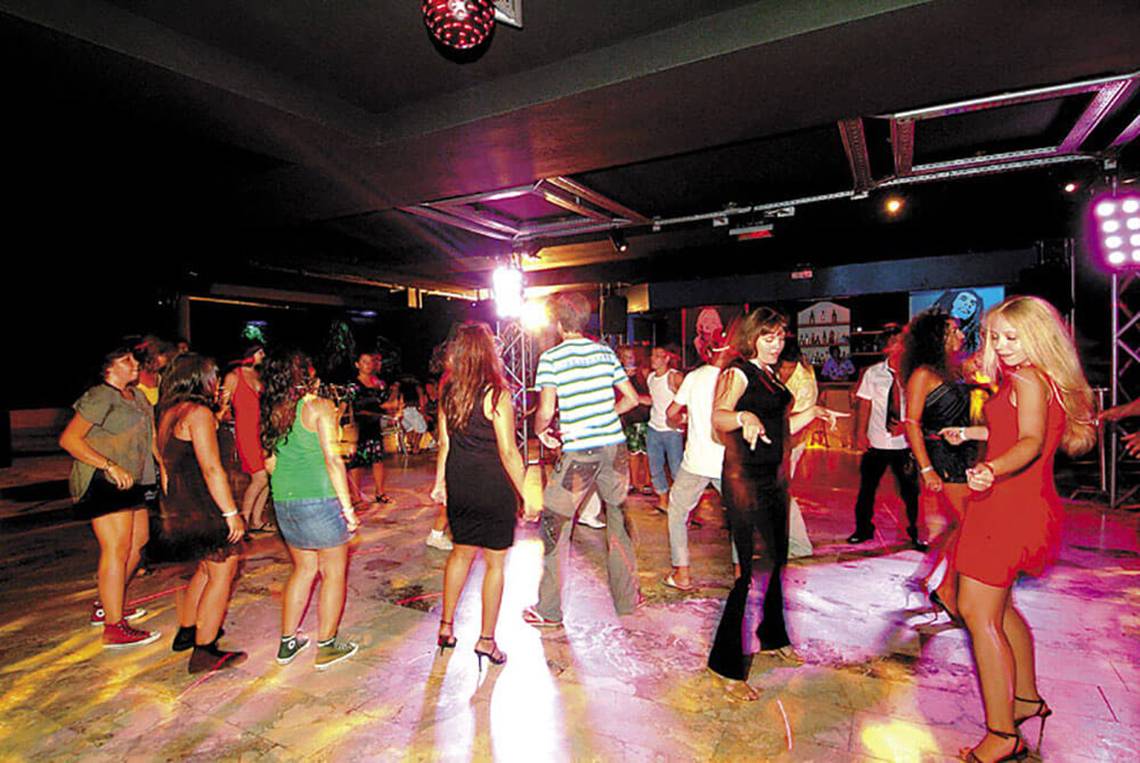 Leute tanzen in der Club Nena Nachtclub, einige mit High Heels und anderen in lässiger Kleidung.