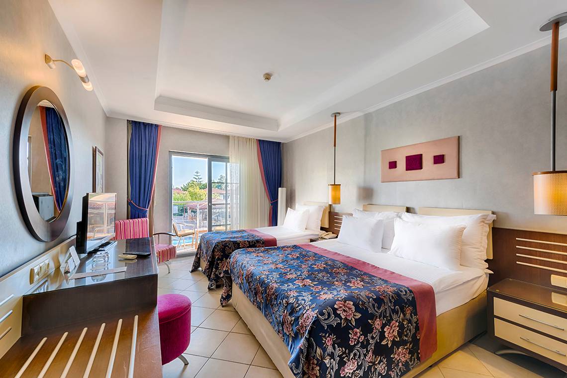 Doppelzimmer im Club Nena Hotel mit zwei Betten, Fernseher, und einem Balkon.