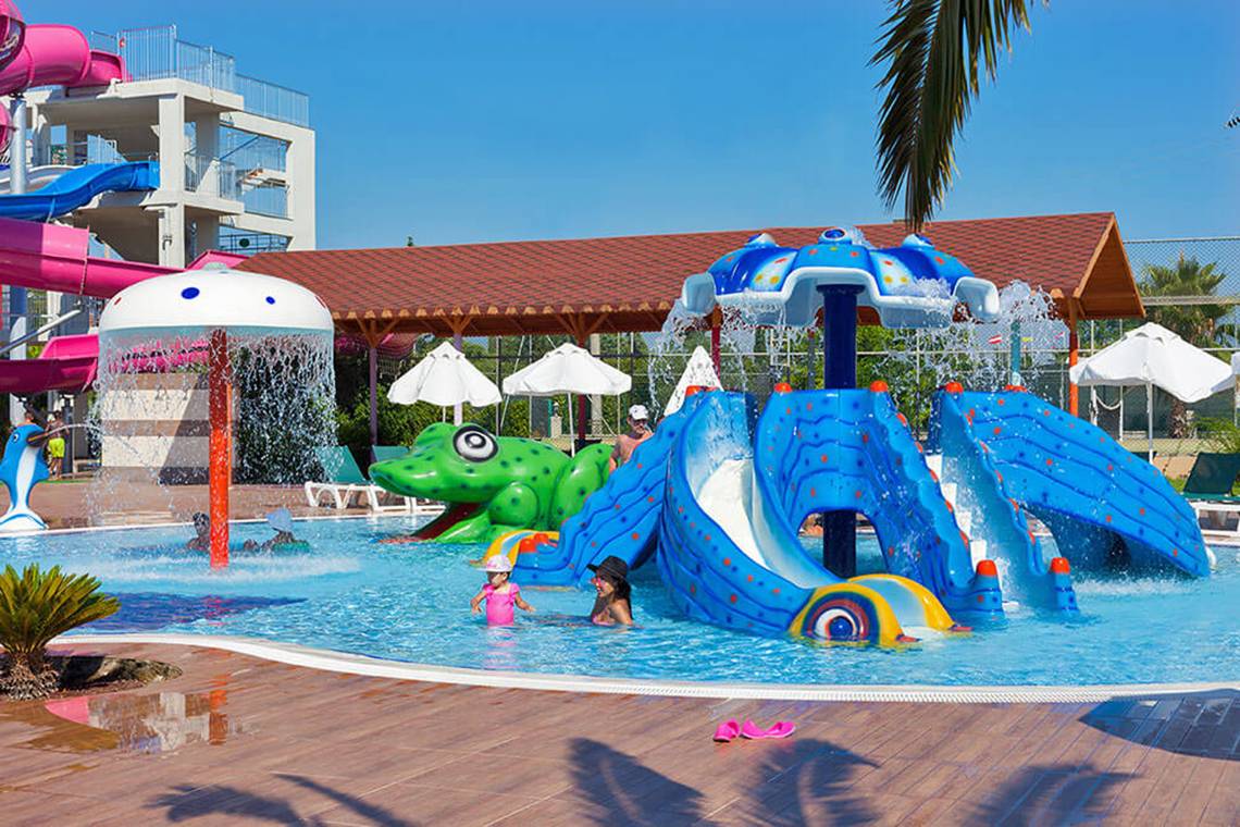 Wasserspielplatz im Club Nena Hotel mit bunten Wasserrutschen und einem Delphinbrunnen.