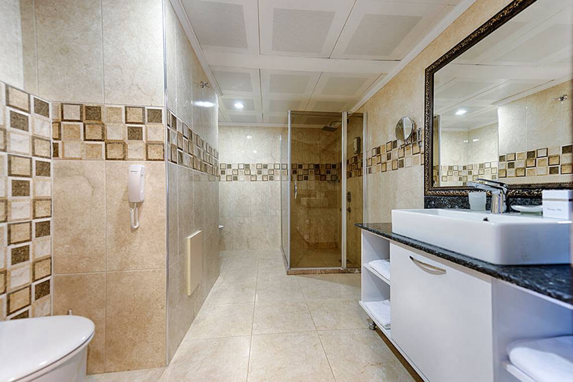 Badezimmer im Club Nena Hotel mit Dusche, Toilette, Waschbecken und Spiegel.
