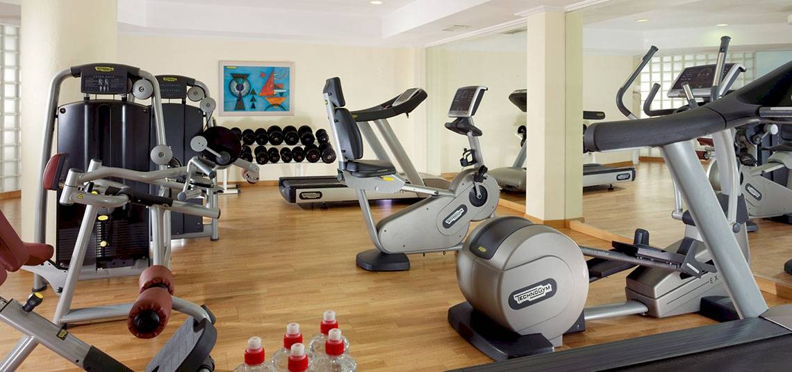 Fitnessstudio im Mykonos Grand Hotel mit verschiedenen Geräten und einer gespiegelten Wand.