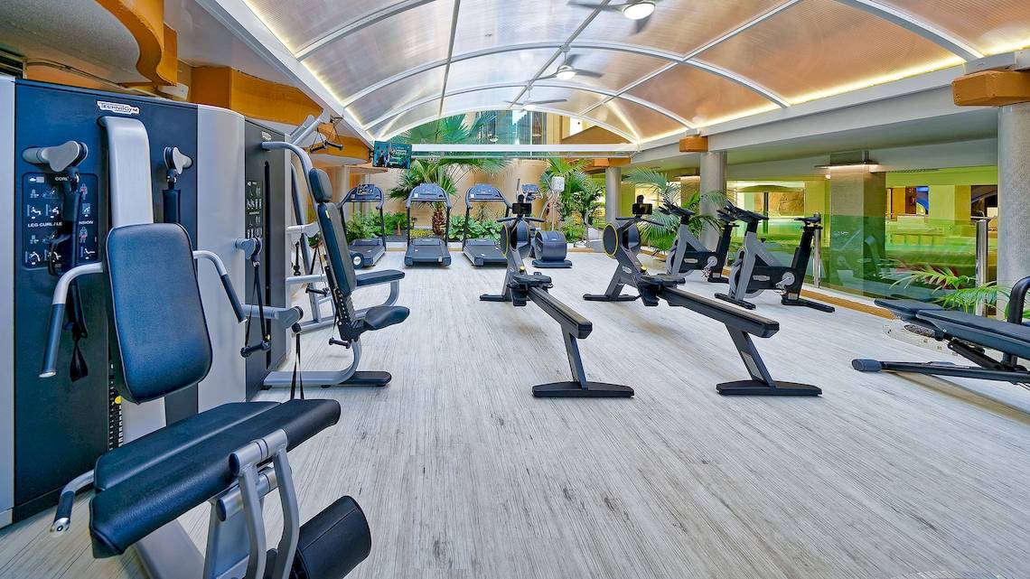 Fitness-Center im Bull Dorado Beach & Spa Hotel mit verschiedenen Geräten und Pflanzen.