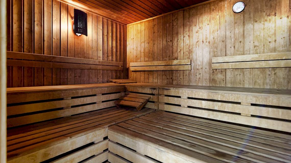 Innenansicht der Sauna im Bull Dorado Beach & Spa Hotel mit Holzbänken und einer Wanduhr.