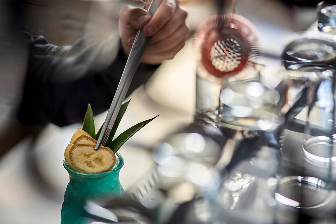Cocktail-Zubereitung im Albatros Spa & Resort mit Blick auf einen grünen Cocktail mit Bananenscheibe.